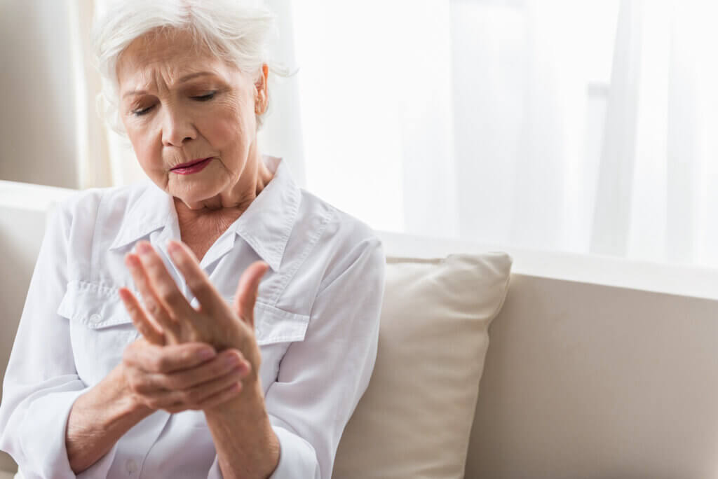 Elderly lady is enduring strong ache in palm of her hand